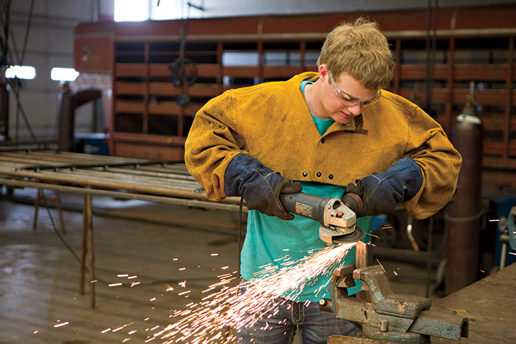 A member Grant Driskell grinds metal in Marshall High School’s ag mechanics class.