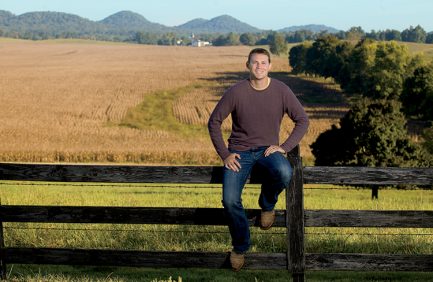 Quint Pottinger sits on a fence overlooking his corn fields which are almost ready for harvest on his farm in New Haven, Kentucky.