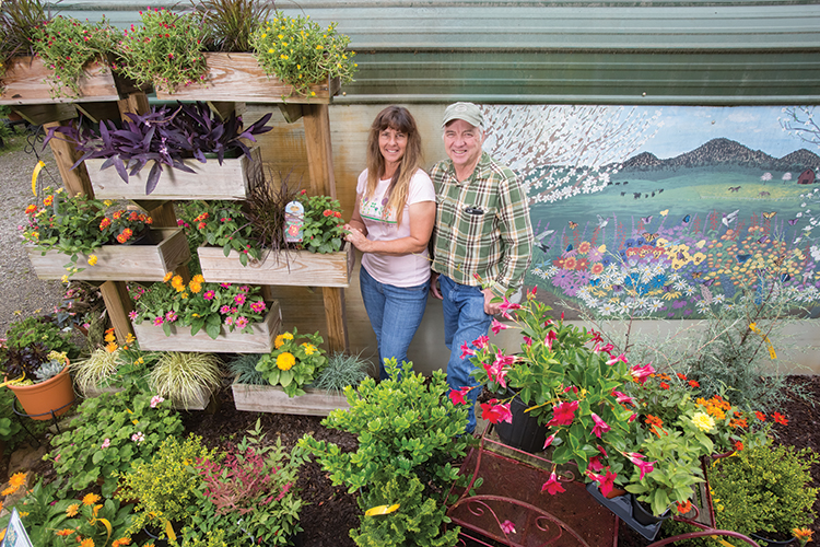 Kellie and Tim Bowen stock plants at their nursery, Full Bloom Nursery, located in Clermont, while employees Monica Chandler and Susanne Keller maintain flowers in a greenhouse.