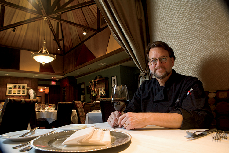Chef Kurt Fleischfresser sits at one of the dinning booths  of Coach House restaurant.