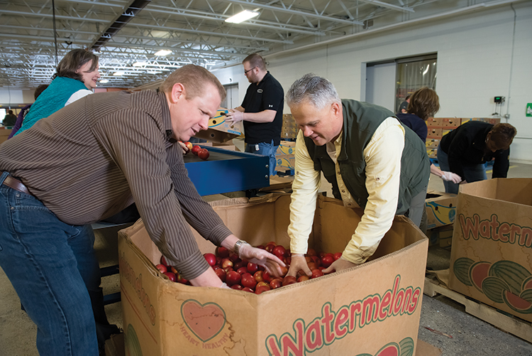 Volunteers sort and box apples for distribution.