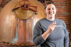 Head distiller Lorna Conrad checks the quality of spirits that she distills using the 240-gallon copper pot still at Corsair Artisan Distillery.