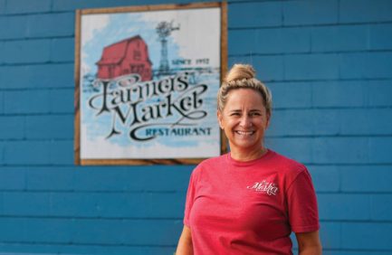 Portrait of Betsy Barnwell in front of the Farmers Market sign