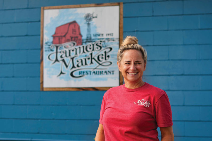 Betsy Barnwell in front of the Farmers Market sign