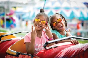 Two little girls pose for a picture on a fair ride