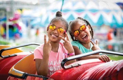 Two little girls pose for a picture on a fair ride