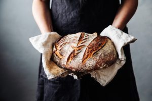 Woman with fresh baked sourdough bread in kitchen