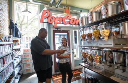 Father and daughter sample popcorn flavors at Cravings Gourmet Popcorn