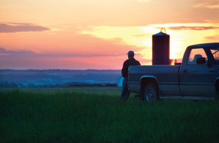 Farmer overlooks farm at sunrise