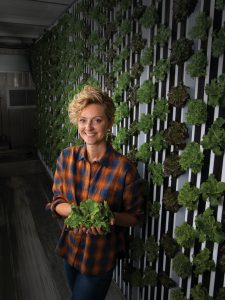 Jill Frey with some of her harvest in front of the grow wall 