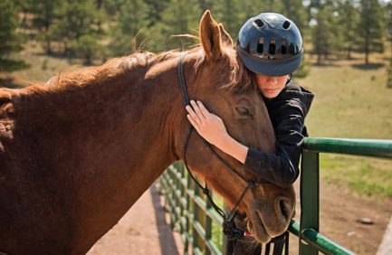 Child hugs one of the horses at Nighthawk Ranch