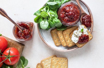 tomato jam on plate with crackers, cheese and fresh basil