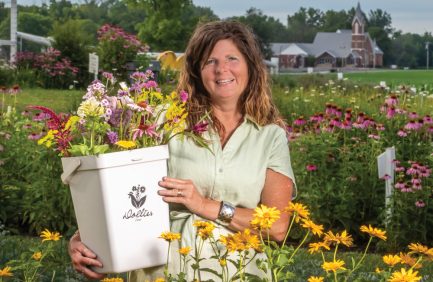 Tricia Wilson holding a bucket of flowers at her Indiana flower farm, Dollie's Farm