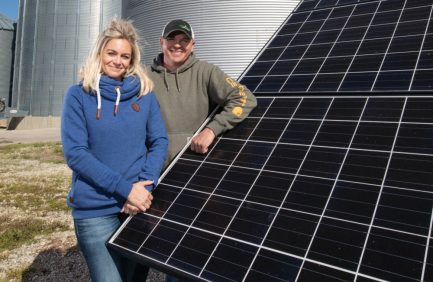 Kelli and Ryan Chalfant stand by the solar panels that power their grain bins at Chalfant Family Farms in Farmland.