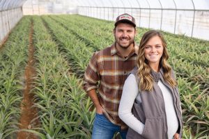 Zach and Kyndle Erhard stand in a greenhouse surrounded by young pineapple plants at Oak Grove Farms in Gallatin, Tennessee. Experimental ag